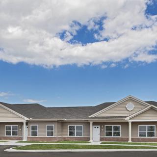 A single-story residential building under a partly cloudy sky.