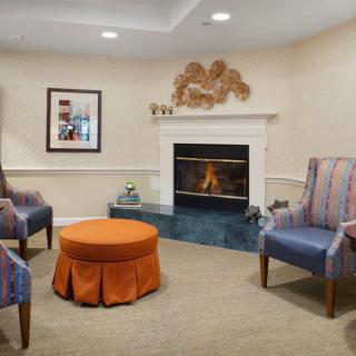 A cozy living room featuring a fireplace, armchairs, and a central coffee table.