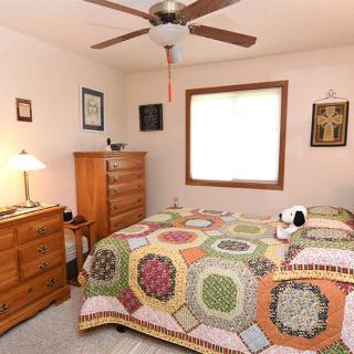 A cozy bedroom with colorful quilt and wooden furniture.