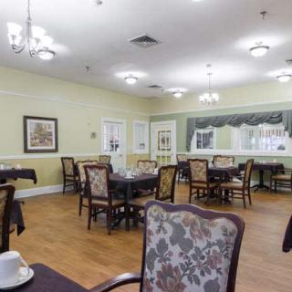A well-decorated dining room with multiple tables and chairs, featuring elegant light fixtures and a wooden floor.