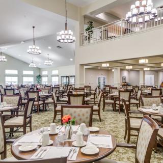 A spacious dining room with neatly arranged tables and elegant chandeliers.