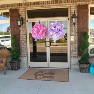 A charming storefront decorated with large flower arrangements and greenery.