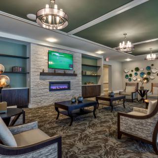 A modern lounge with comfortable seating, chandeliers, and a fireplace.
