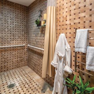 A stylish bathroom features patterned tiles, a cozy robe, and lush plants for a relaxing ambiance.