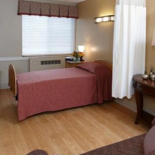 A cozy, well-lit bedroom with a single bed and wooden flooring.