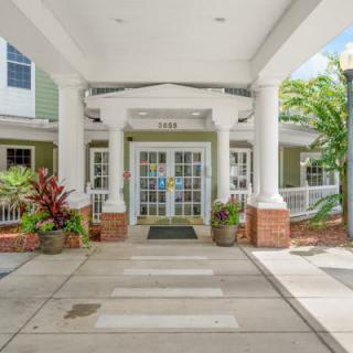 The entrance of a building featuring columns and surrounding plants.