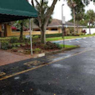 A parking area with a nearby building and trees under an overcast sky.