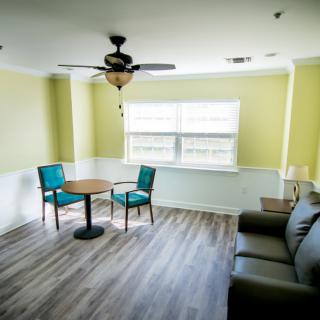 A cozy living room with a small table and chairs, a sofa, and a ceiling fan.