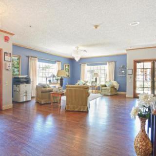 A spacious living room with hardwood floors, comfortable seating, and large windows.