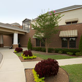 A modern brick building with landscaped gardens and a walkway.