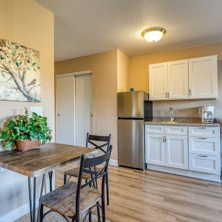 A cozy kitchen and dining area featuring a wooden table with chairs, a compact refrigerator, and white cabinetry.