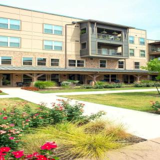 A modern residential apartment building with well-maintained gardens in front.