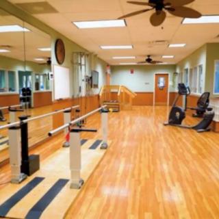 A well-equipped fitness room with exercise machines and mirrors lining the walls.