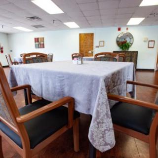 A neatly set dining room table with a white tablecloth and wooden chairs in a spacious interior.
