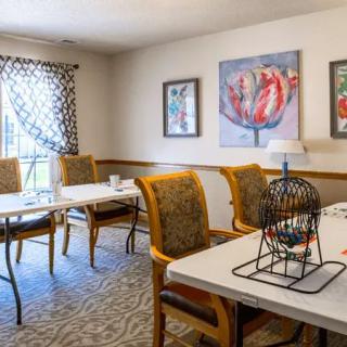A meeting room with tables and chairs, decorated with art pieces on the walls and a patterned carpet.
