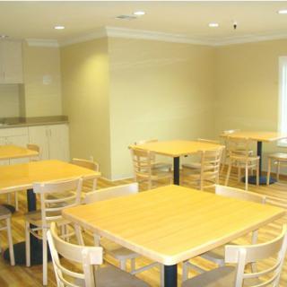 A well-lit dining area with several wooden tables and chairs arranged neatly.