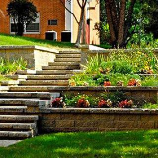 A beautifully landscaped garden with terraced plant beds and stone stairs.
