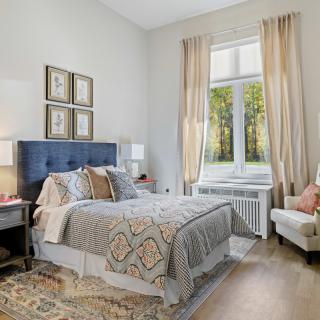 A well-decorated bedroom with a plush bed, elegant decor, and a large window with curtains.