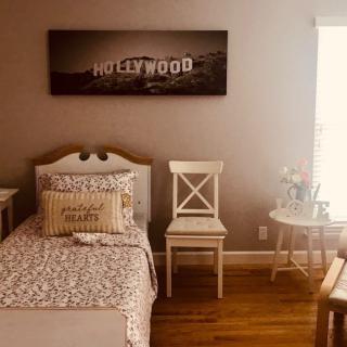 A cozy bedroom featuring Hollywood-themed artwork above a neatly made bed and chairs.