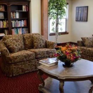 A cozy living room with a patterned sofa, bookshelf, coffee table, and indoor plant.