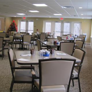 An empty dining area with neatly arranged tables and chairs, featuring bright lighting and a cozy atmosphere.