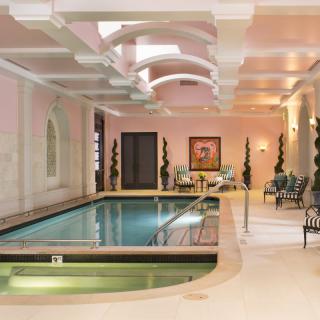 A luxurious indoor swimming pool surrounded by elegant architectural details and comfortable seating areas.