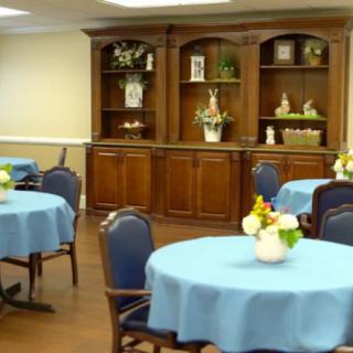A nicely decorated dining room with tables covered in blue tablecloths, arranged with floral centerpieces.
