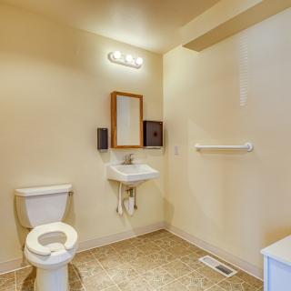 A simple bathroom with a toilet, sink, mirror, and towel rack.