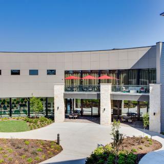 A modern building entrance with landscaped surroundings on a clear day.