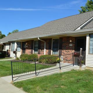 A row of suburban houses with a grassy lawn and pathways.