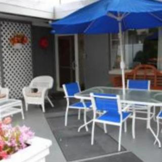 A cozy patio setup with a glass-top table, blue chairs, and an umbrella.