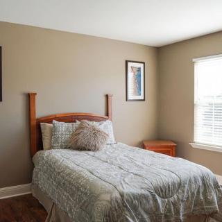 A simple bedroom with a single bed, nightstand, and window.