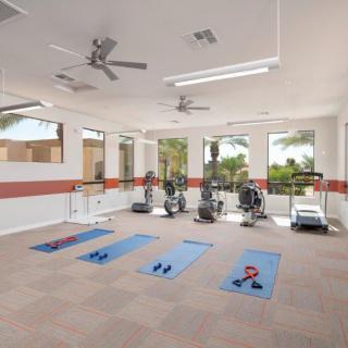 A well-lit gym equipped with exercise machines, yoga mats, and weights.