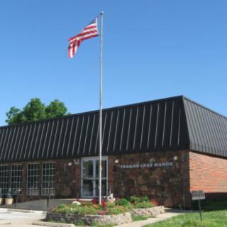 A small library building with an American flag flying outside on a clear day.