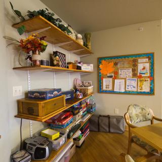 A cozy room with shelves filled with board games and toys, a bulletin board on the wall, and comfortable seating.
