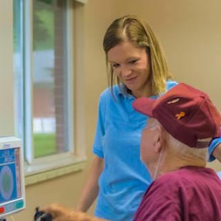 A healthcare professional engages with an elderly patient in a supportive and friendly environment.