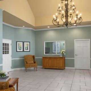 A spacious lobby with a chandelier, seating, and a reception desk.