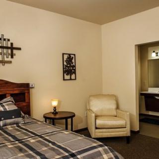 Cozy bedroom with a bed, armchair, and warm lighting.