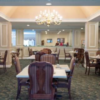 An elegant dining room with multiple tables and chairs, featuring a chandelier.