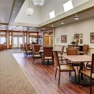 A spacious dining area with wooden tables and chairs, featuring warm lighting and elegant decor.