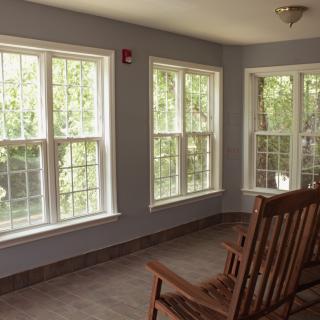 A cozy sunroom with large windows allowing natural light to fill the space, featuring a comfortable rocking chair.