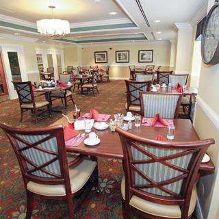 A well-lit dining area with neatly arranged tables and chairs, featuring a formal setting.