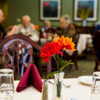 A beautifully set table in a restaurant, featuring vibrant flowers and elegant glassware.
