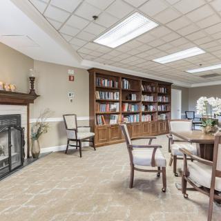 A cozy library space with a fireplace, bookshelves, and seating for reading.