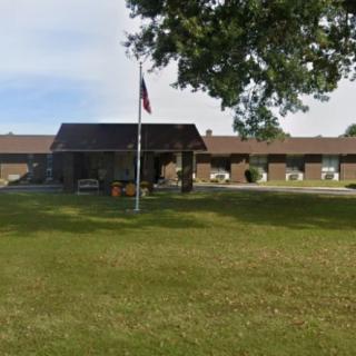 A building with a flagpole and a tree in the foreground.
