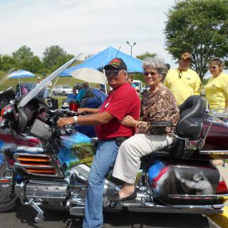 A couple enjoys a motorcycle ride at an outdoor event.