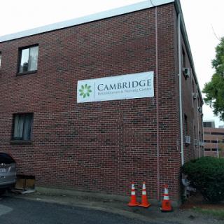 A brick building featuring a sign for 'Cambridge' with parking cones in front.