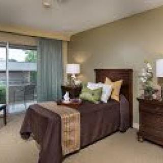 A cozy bedroom with a neatly made bed, nightstands, and soft lighting.