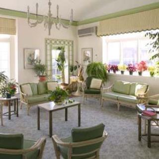A bright living room with green furniture and an abundance of plants.