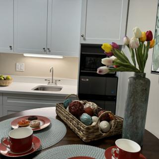 A modern kitchen with a stylish table setting, featuring colorful tulips in a vase and decorative items on the table.